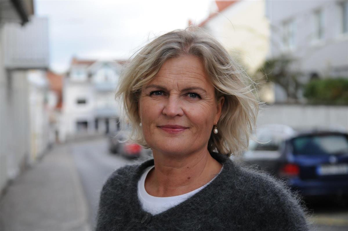 Profilbilete av regionsjef for Rogaland der ho står i ei bygate med parkerte bilar - Klikk for stort bilete